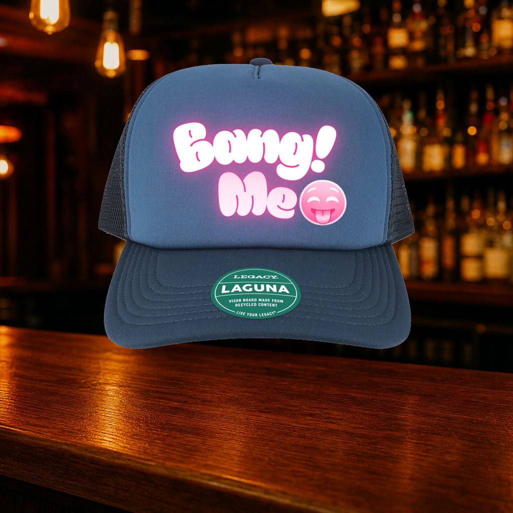 Bang Me Trucker Hat shown against a warm after-dark bar backdrop