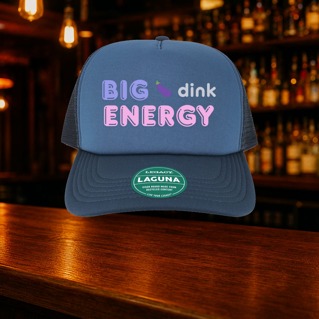 Big Dink Energy Trucker Hat — Blue variety shown against a warm after-dark bar backdrop