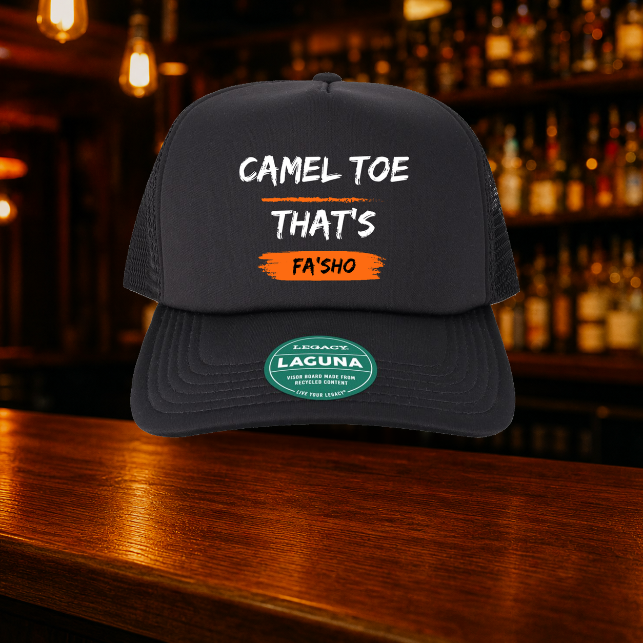 Camel Toe That's Fa'sho Trucker Hat — All Black variety shown against a warm after-dark bar backdrop