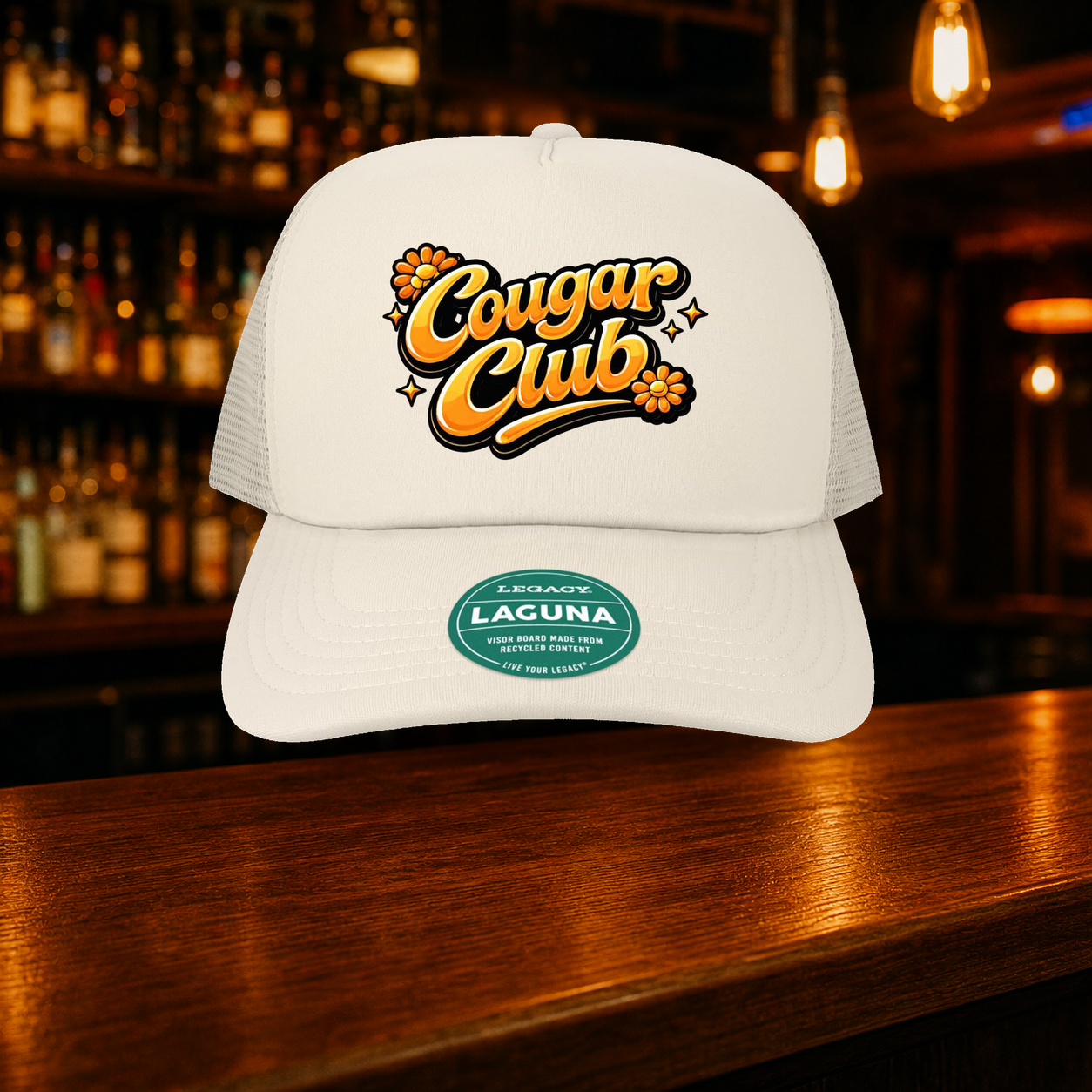 Cougar Club Trucker Hat shown against a warm after-dark bar backdrop