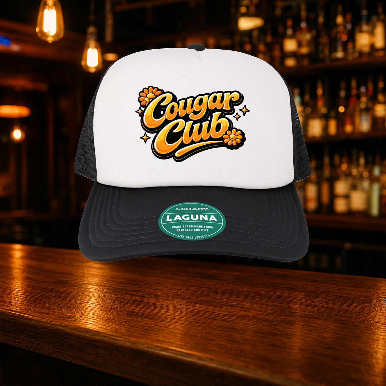 Cougar Club Trucker Hat — Black variety shown against a warm after-dark bar backdrop