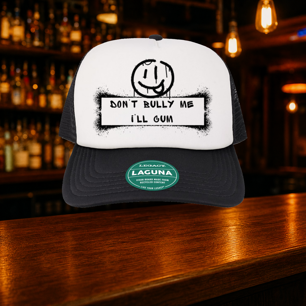 Don't Bully Me I'll Cum Trucker Hat shown against a warm after-dark bar backdrop