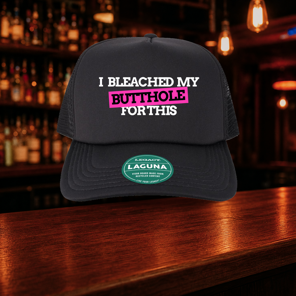 I Bleached My Butthole for This Trucker Hat shown against a warm after-dark bar backdrop