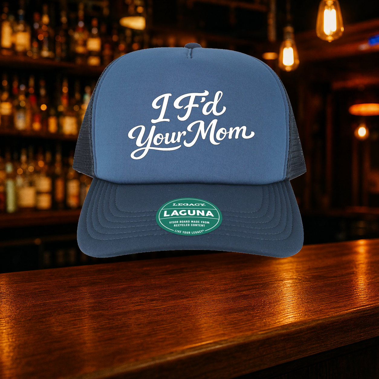 I F'd Your Mom Trucker Hat shown against a warm after-dark bar backdrop