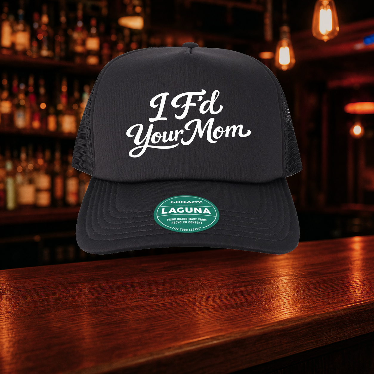 I F'd Your Mom Trucker Hat — All Black variety shown against a warm after-dark bar backdrop