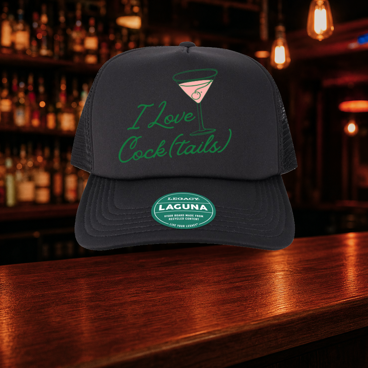 I Love Cocktails Trucker Hat shown against a warm after-dark bar backdrop