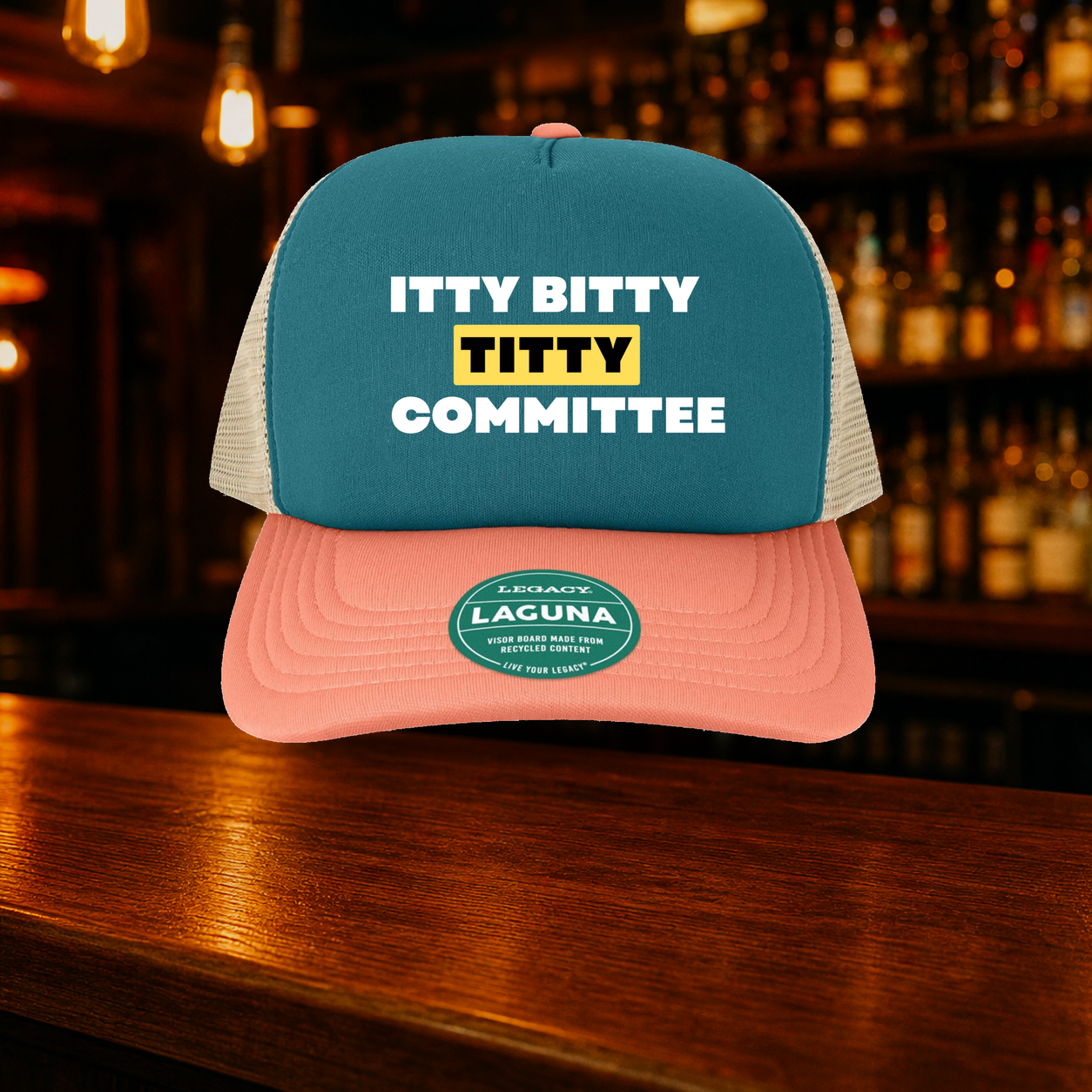 Itty Bitty Titty Committee Trucker Hat — Marine variety shown against a warm after-dark bar backdrop