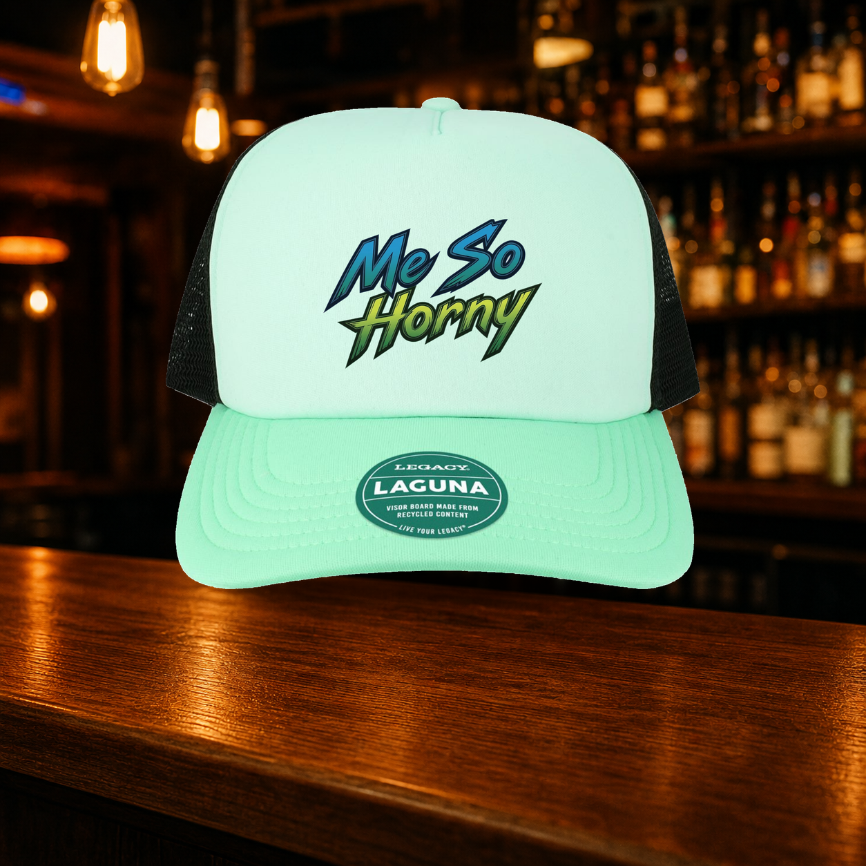 Me So Horny Trucker Hat — Teal variety shown against a warm after-dark bar backdrop
