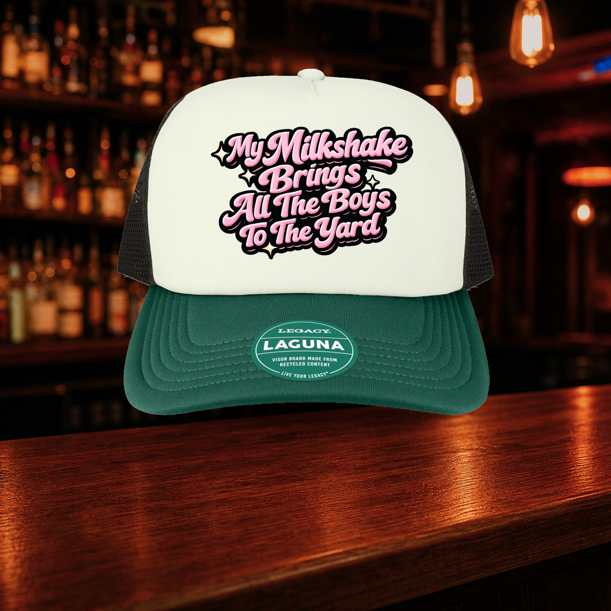 My Milkshake Bring All the Boys to the Yard Trucker Hat — Green variety shown against a warm after-dark bar backdrop