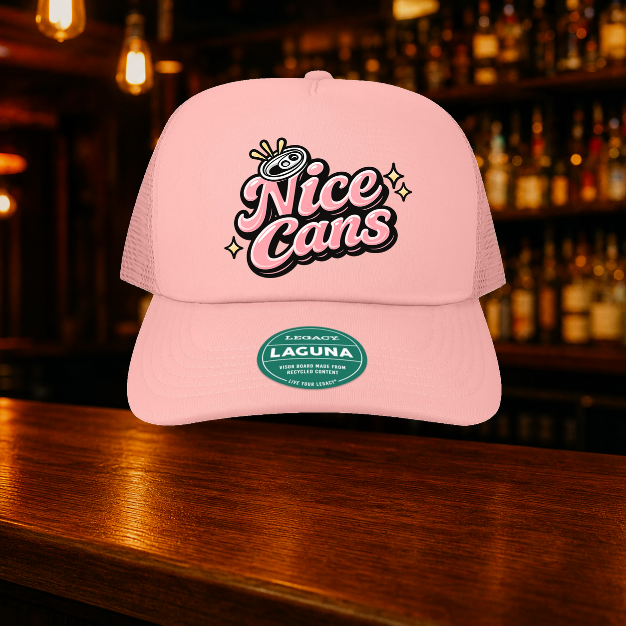 Nice Cans Trucker Hat — Pink variety shown against a warm after-dark bar backdrop